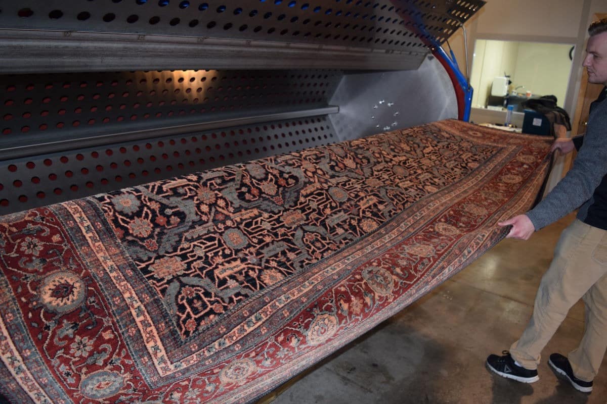 Rug technician performing hands-on restoration work at the Rug Life facility